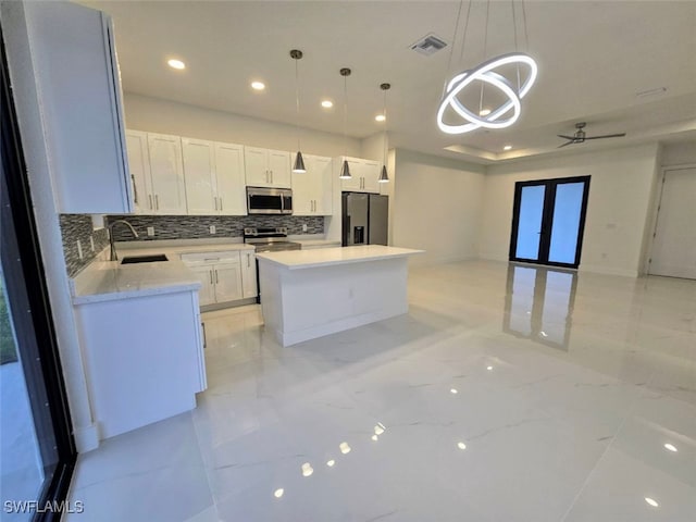 kitchen with white cabinets, sink, hanging light fixtures, a kitchen island, and stainless steel appliances