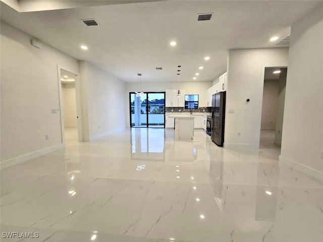 interior space featuring white cabinets, a center island, decorative light fixtures, and black fridge