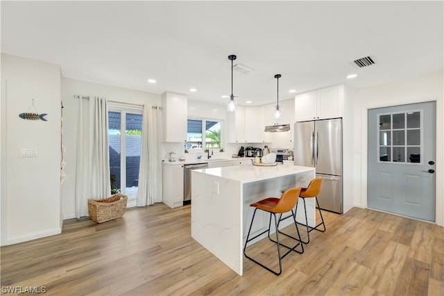 kitchen with a center island, light hardwood / wood-style flooring, appliances with stainless steel finishes, and white cabinetry