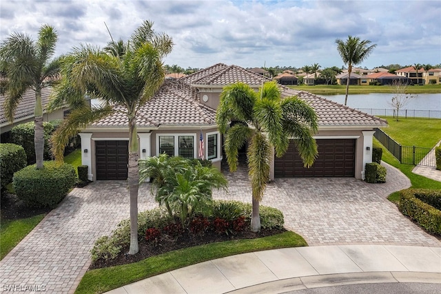 mediterranean / spanish-style home with a water view, a front yard, and a garage