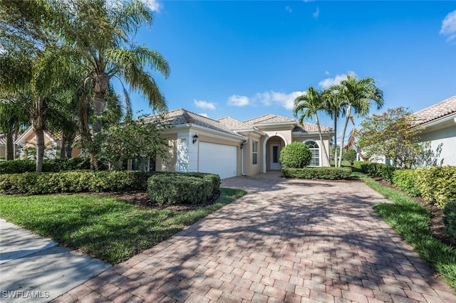 mediterranean / spanish-style house featuring decorative driveway, an attached garage, and stucco siding