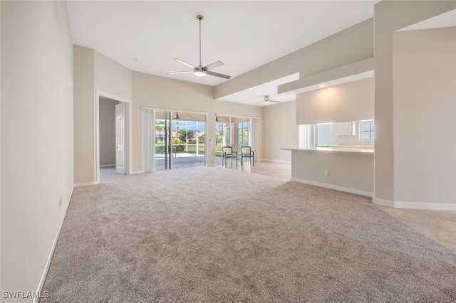 unfurnished room featuring light tile patterned floors, light colored carpet, a high ceiling, ceiling fan, and baseboards