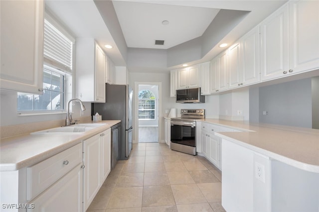 kitchen with light countertops, appliances with stainless steel finishes, a sink, and white cabinetry