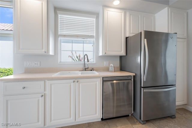 kitchen featuring appliances with stainless steel finishes, light countertops, a sink, and white cabinetry