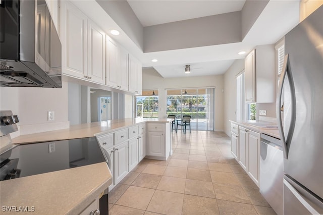 kitchen featuring stainless steel appliances, light countertops, white cabinetry, light tile patterned flooring, and a peninsula