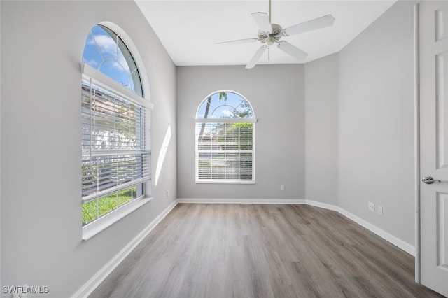 empty room with a ceiling fan, baseboards, and wood finished floors