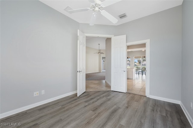 unfurnished room featuring ceiling fan, wood finished floors, visible vents, and baseboards