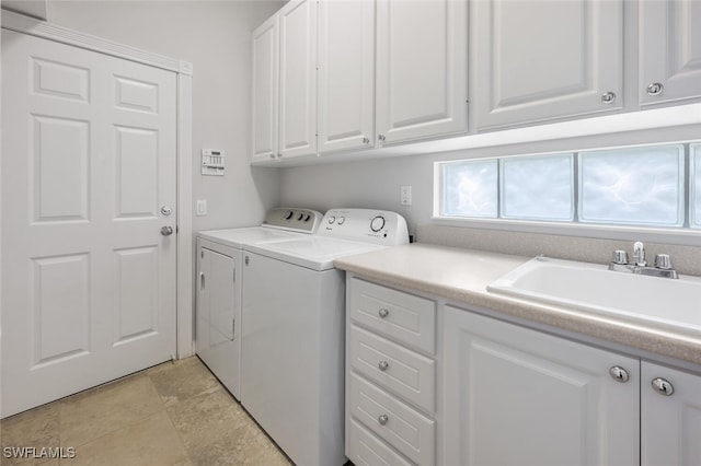 clothes washing area featuring cabinet space, a sink, and washing machine and clothes dryer