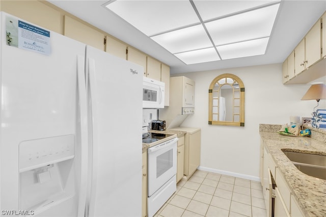 kitchen with cream cabinets, sink, light tile patterned floors, and white appliances