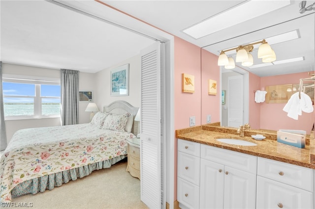 carpeted bedroom featuring a water view and sink