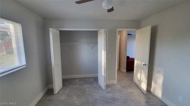 unfurnished bedroom featuring a closet, dark tile floors, ceiling fan, and multiple windows