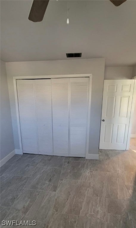 unfurnished bedroom featuring dark tile flooring, a closet, and ceiling fan