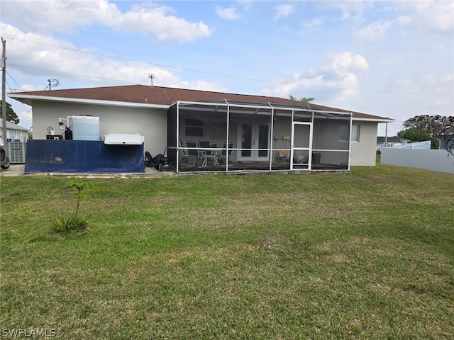 back of property featuring a lanai and a lawn