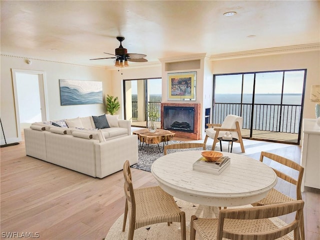 living room with a wealth of natural light, light hardwood / wood-style flooring, a water view, and ceiling fan