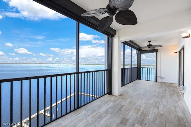 unfurnished sunroom featuring ceiling fan and a water view