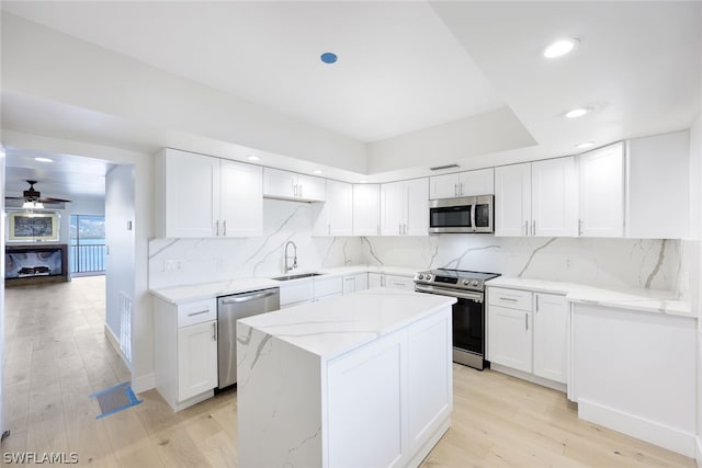 kitchen featuring white cabinets, ceiling fan, light wood-type flooring, and stainless steel appliances