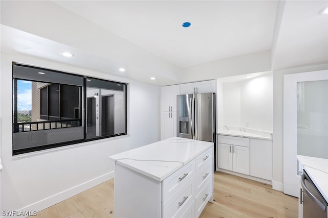 kitchen with white cabinetry, a center island, stainless steel appliances, and light hardwood / wood-style floors