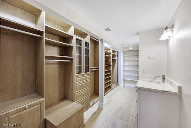 walk in closet with sink and light wood-type flooring