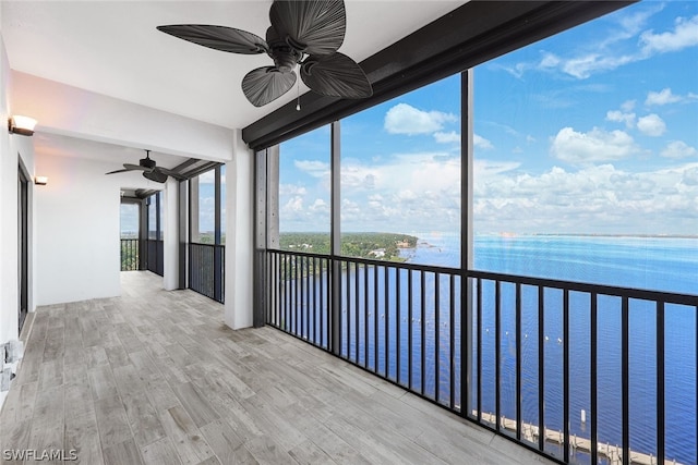 unfurnished sunroom with ceiling fan and a water view