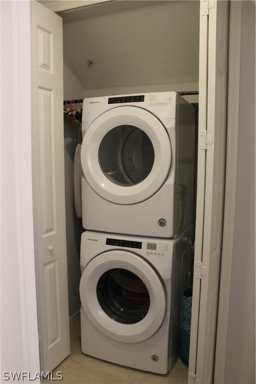 washroom featuring stacked washer and clothes dryer and light tile floors