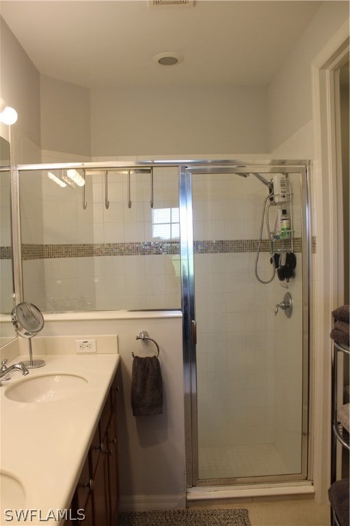 bathroom with dual sinks, large vanity, and an enclosed shower