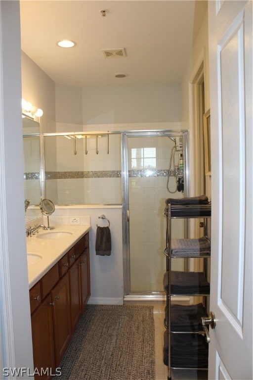 bathroom with double sink vanity and a shower with shower door