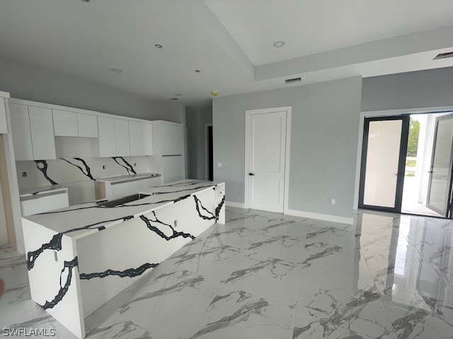 kitchen with white cabinets, light tile patterned floors, backsplash, and a center island