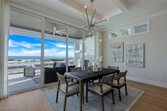 dining space with crown molding, a water view, a chandelier, and light hardwood / wood-style floors