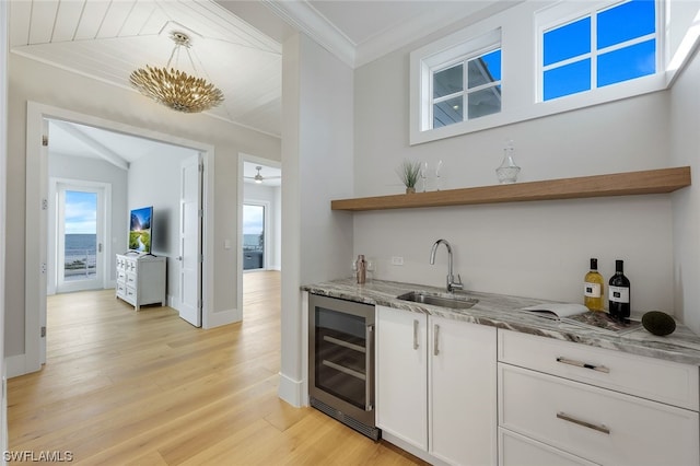 bar with wine cooler, a sink, hanging light fixtures, ornamental molding, and wet bar