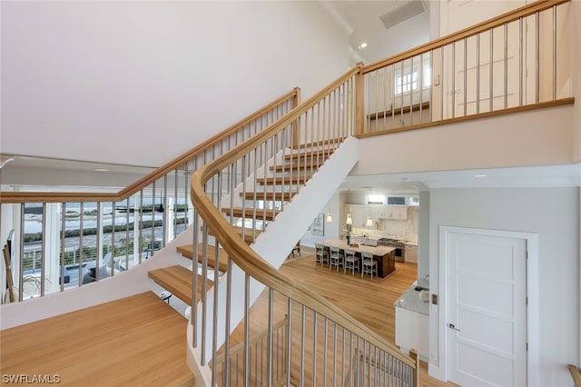 stairway featuring hardwood / wood-style floors and crown molding