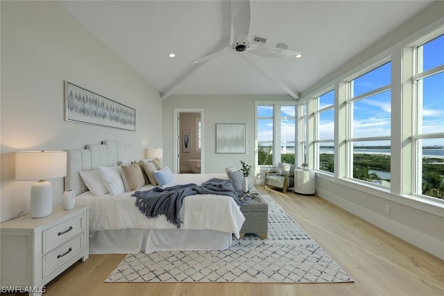 bedroom featuring a water view, vaulted ceiling, ceiling fan, light wood-type flooring, and connected bathroom