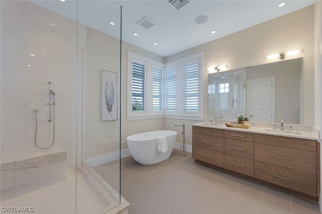 full bath with double vanity, visible vents, a sink, a walk in shower, and a freestanding tub