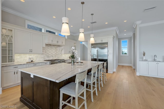 kitchen featuring white cabinetry, an island with sink, and range