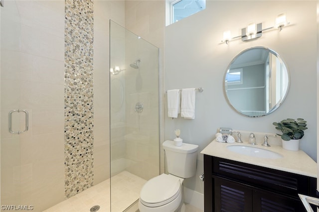 bathroom featuring a tile shower, vanity, and toilet