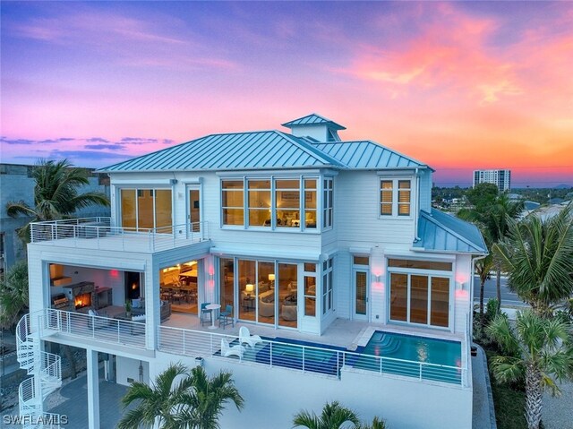 back house at dusk featuring a patio area and a balcony