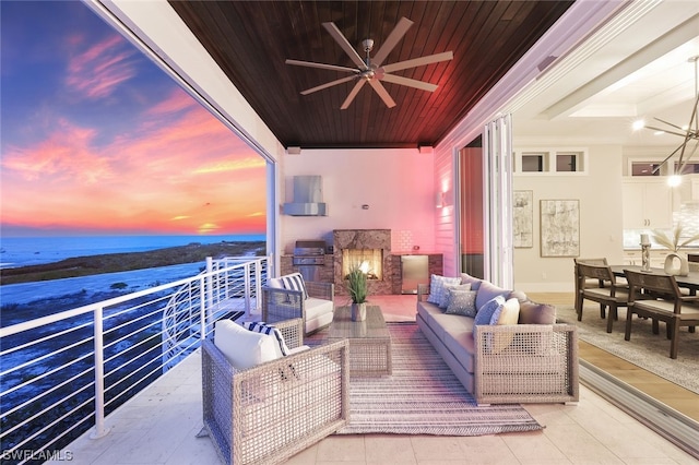 balcony at dusk with ceiling fan, a water view, and an outdoor living space