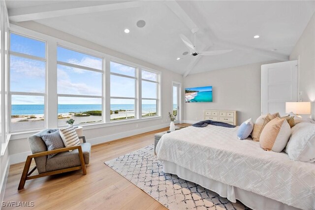 bedroom with vaulted ceiling with beams, a water view, a view of the beach, and light wood-type flooring