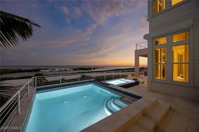 view of pool featuring a water view, a fenced in pool, and an in ground hot tub