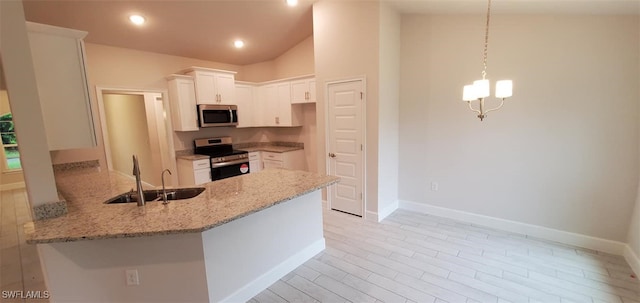 kitchen featuring light stone counters, kitchen peninsula, sink, appliances with stainless steel finishes, and white cabinets