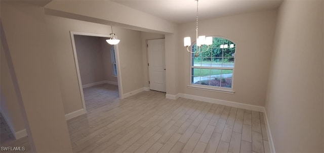 spare room with light wood-type flooring and a chandelier