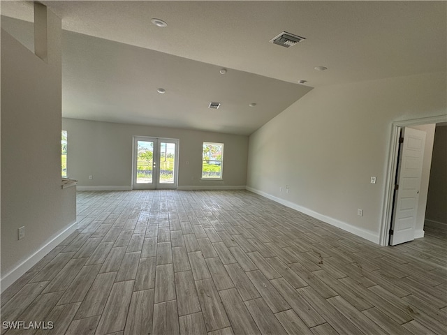 empty room featuring vaulted ceiling and light hardwood / wood-style floors