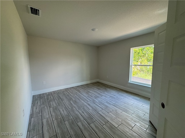 unfurnished room featuring light wood-type flooring and a textured ceiling