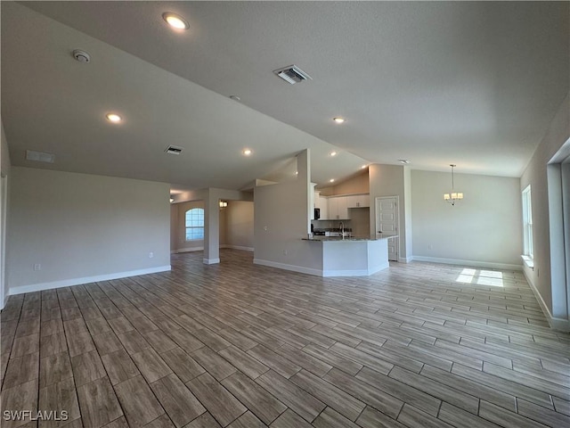 unfurnished living room with an inviting chandelier and vaulted ceiling