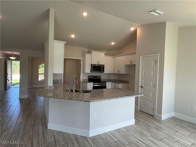 kitchen with vaulted ceiling, white cabinetry, sink, kitchen peninsula, and stainless steel appliances