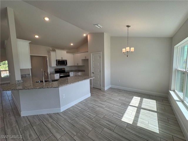 kitchen with sink, dark stone countertops, appliances with stainless steel finishes, kitchen peninsula, and white cabinets