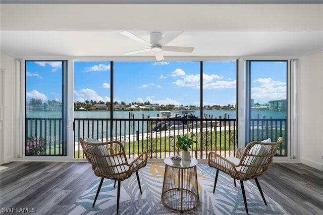 sunroom / solarium with ceiling fan, a water view, and a wealth of natural light