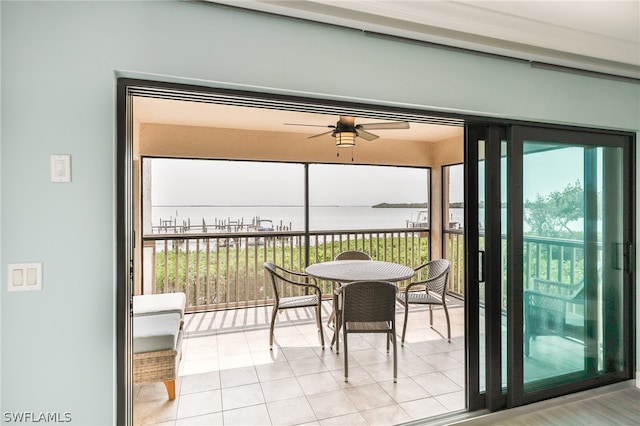 sunroom featuring ceiling fan and a water view