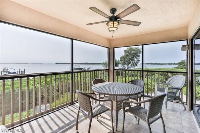 sunroom / solarium featuring a water view and ceiling fan