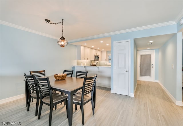 dining space featuring ornamental molding and light hardwood / wood-style flooring