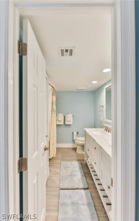 bathroom with toilet, hardwood / wood-style floors, and oversized vanity